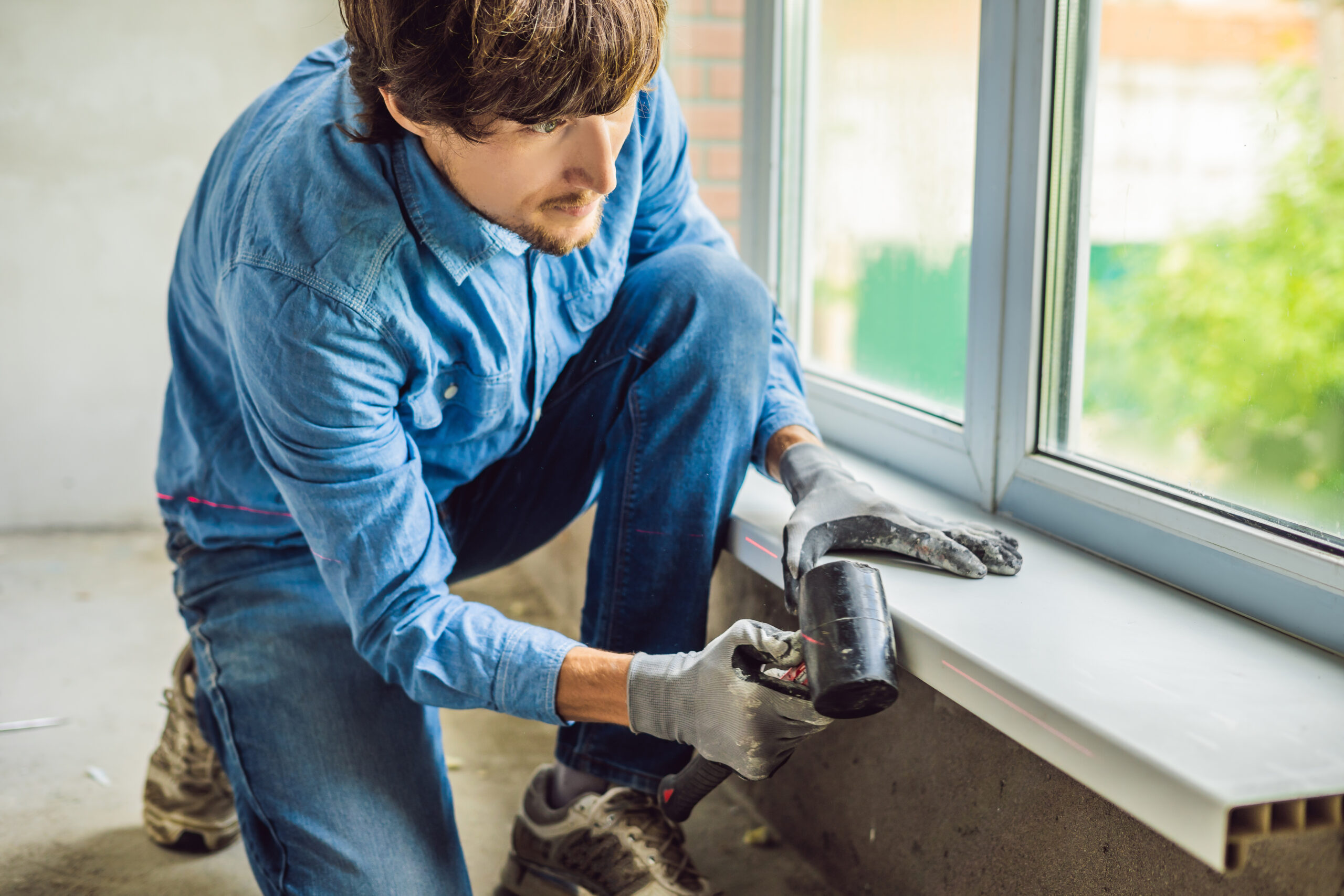 Man in a blue shirt does window installation.